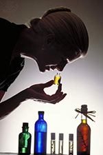 A woman smells one of several bottles of aromatherapy oil.