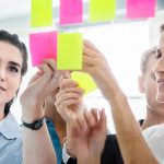 young professional females creating kanban chart with post its