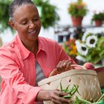 mujer afroamericana comprando verduras frescas en el mercado agrícola