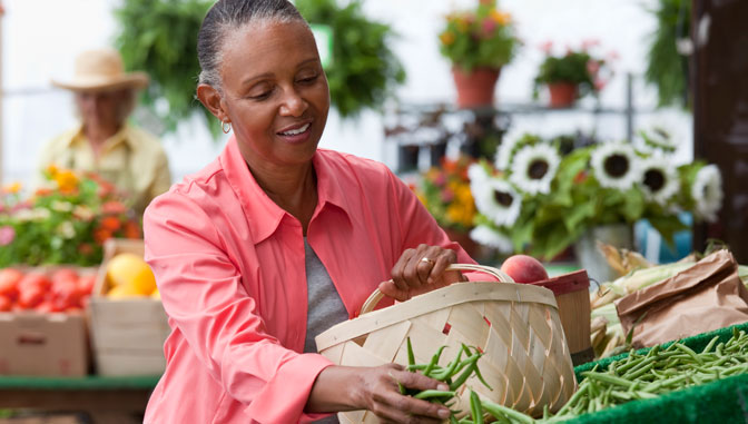 mujer afroamericana comprando verduras frescas en el mercado agrícola