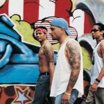 african american gentleman walking in front of graffiti