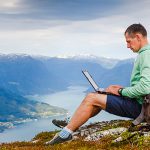 student on top of a mountain with laptop