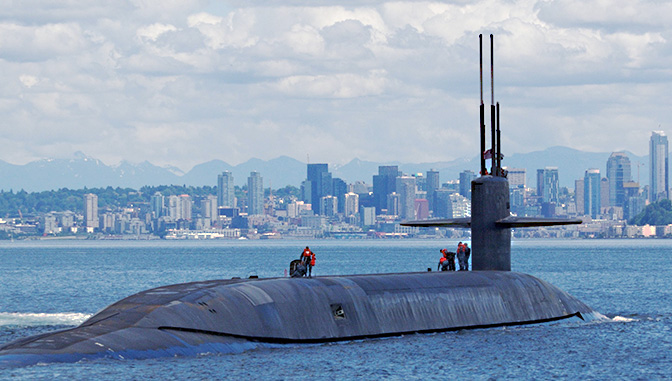 submarine emerging from the water in front of a city