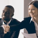 women and african american man in suits shaking hands