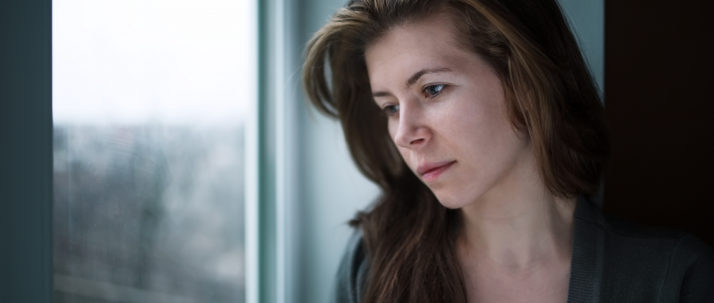 depressed woman staring blankly out the window