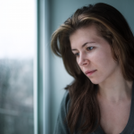 depressed woman staring blankly out the window