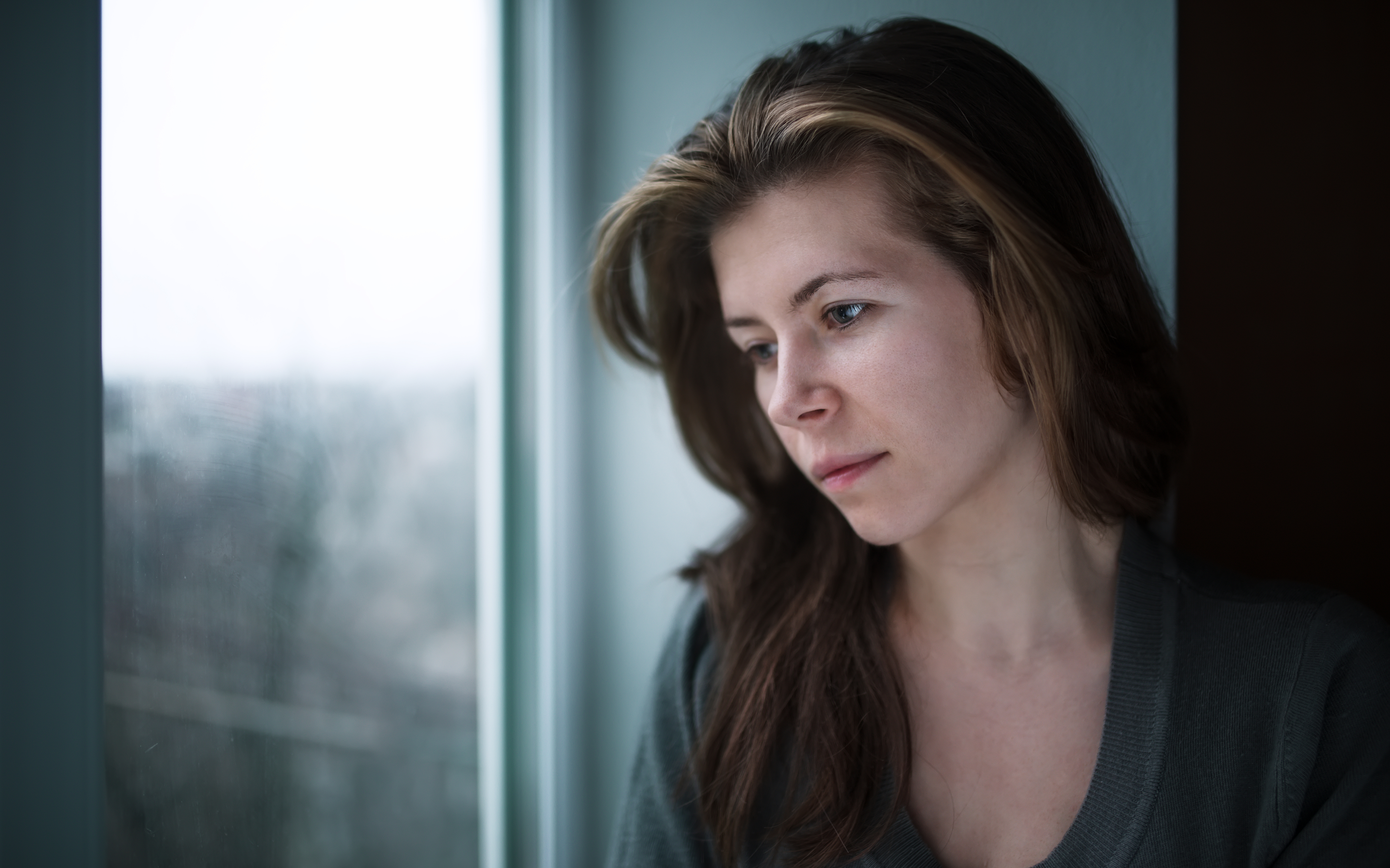 depressed woman staring blankly out the window