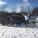 Andrew Lieberam jumping for joy in front of Excelsior College sign