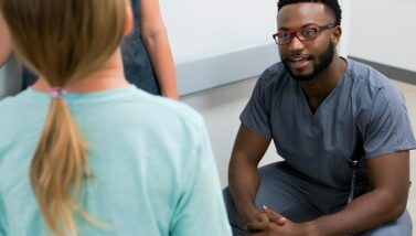 Male nursing student engages in discussion with other Excelsior University students