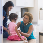 african american nurse doing a check up on a young asian girl and her mother