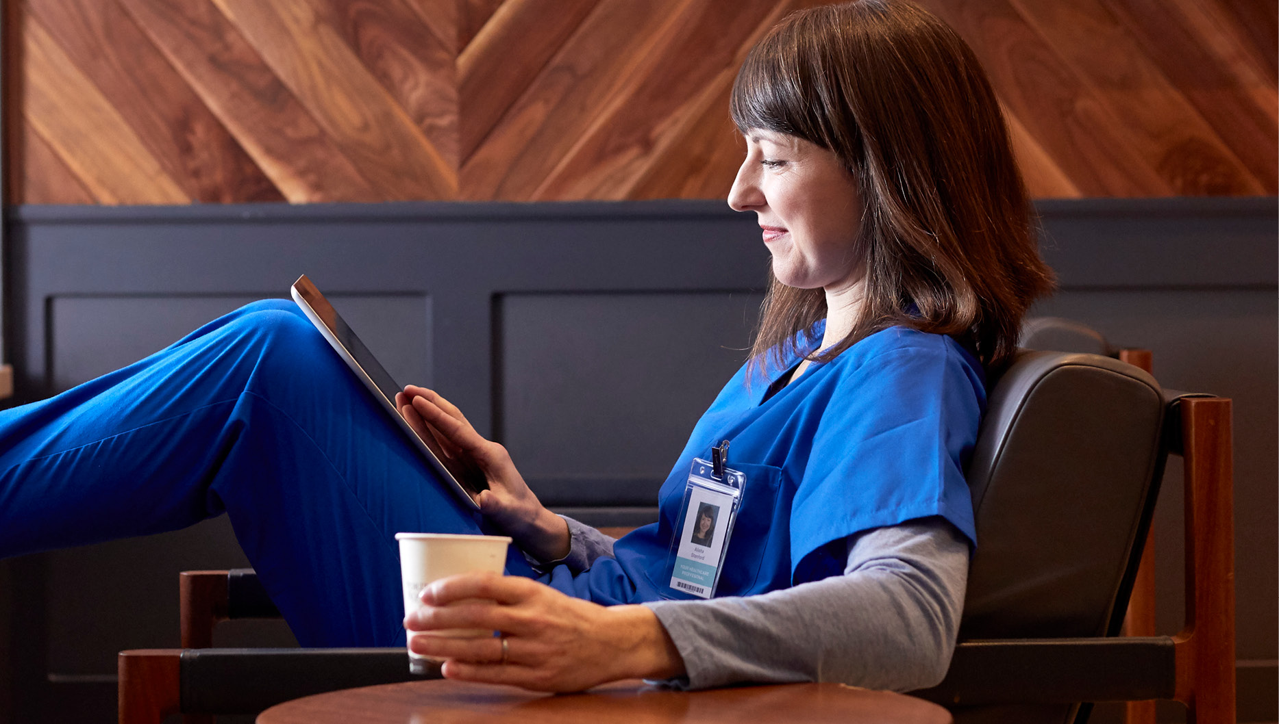 female nurse in scrubs practicing self care, drinking coffee