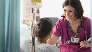 Smiling nurse with a patient in a hospital room
