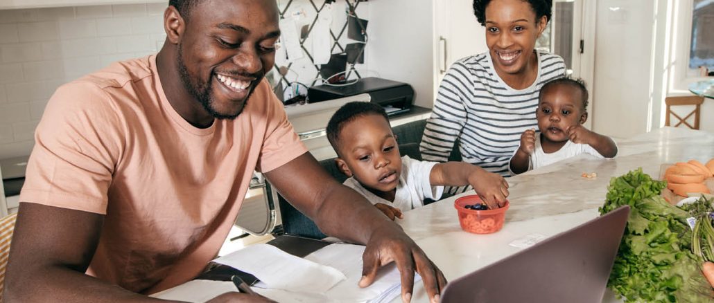 African American Man on Laptop surrounded by wife and kids