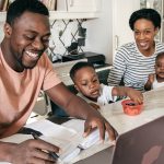 African American Man on Laptop surrounded by wife and kids