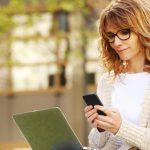 mujer caucásica usando un portátil y un smartphone para estudiar