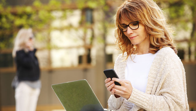 caucasian woman using laptop and smartphone to study