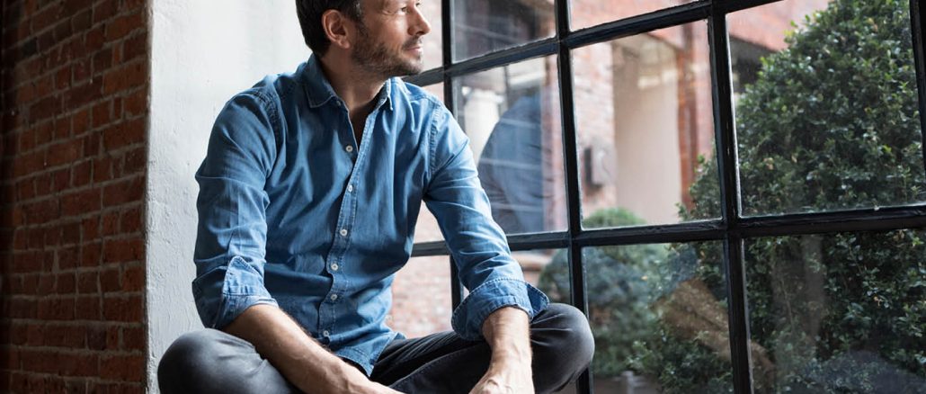 man contemplating an online masters degree out a window