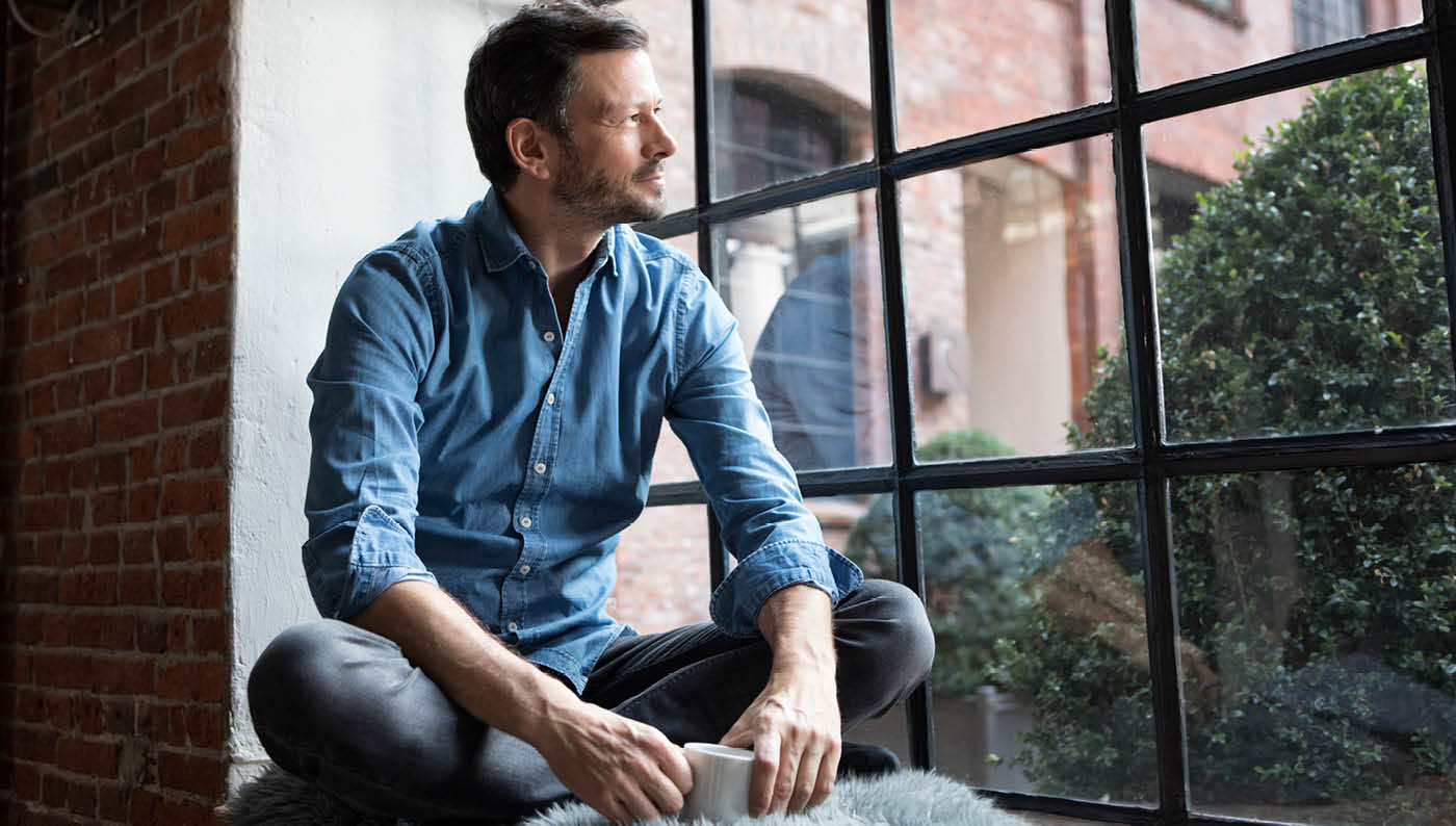 man contemplating an online masters degree out a window