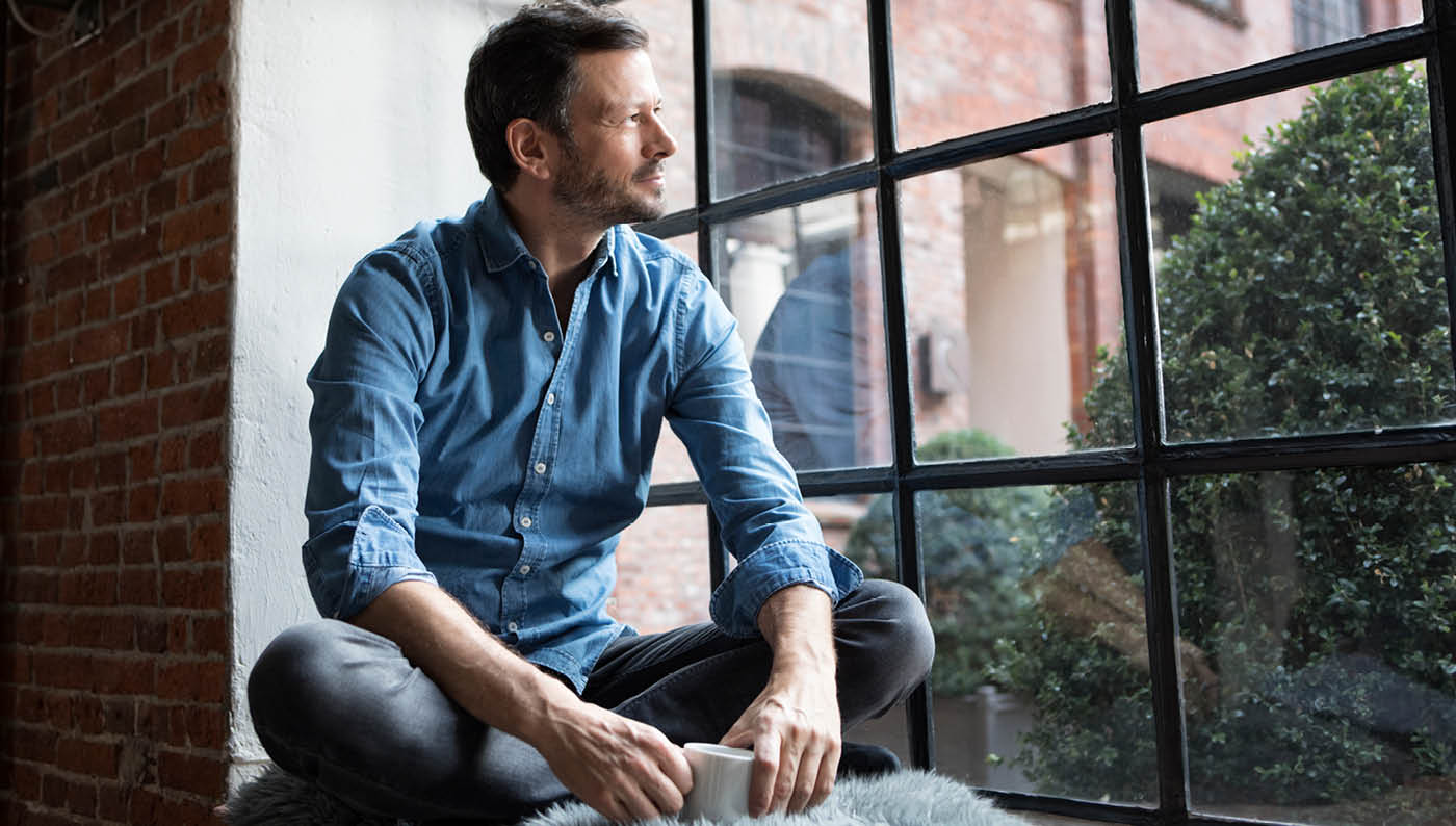 hombre contemplando un máster online por una ventana