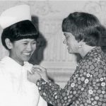 Carrie B. Lenburg poniendo un broche a una graduada en enfermería