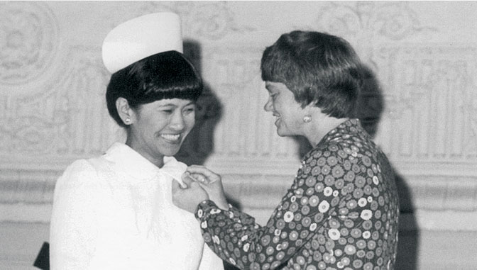 Carrie B. Lenburg poniendo un broche a una graduada en enfermería