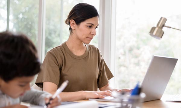 Enlisted woman using her laptop with son nearby