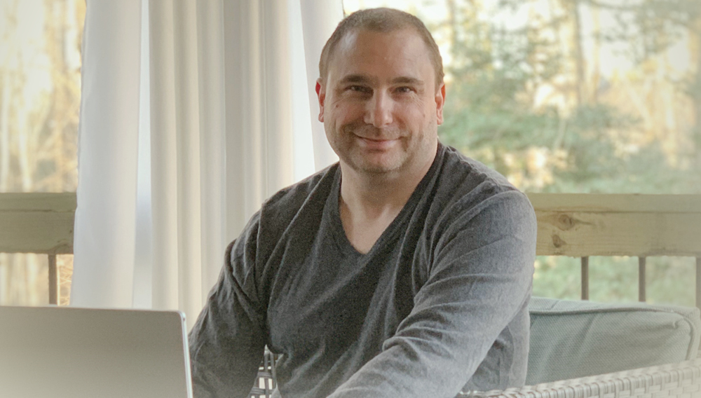 Christopher Johnson sitting at desk looking at camera