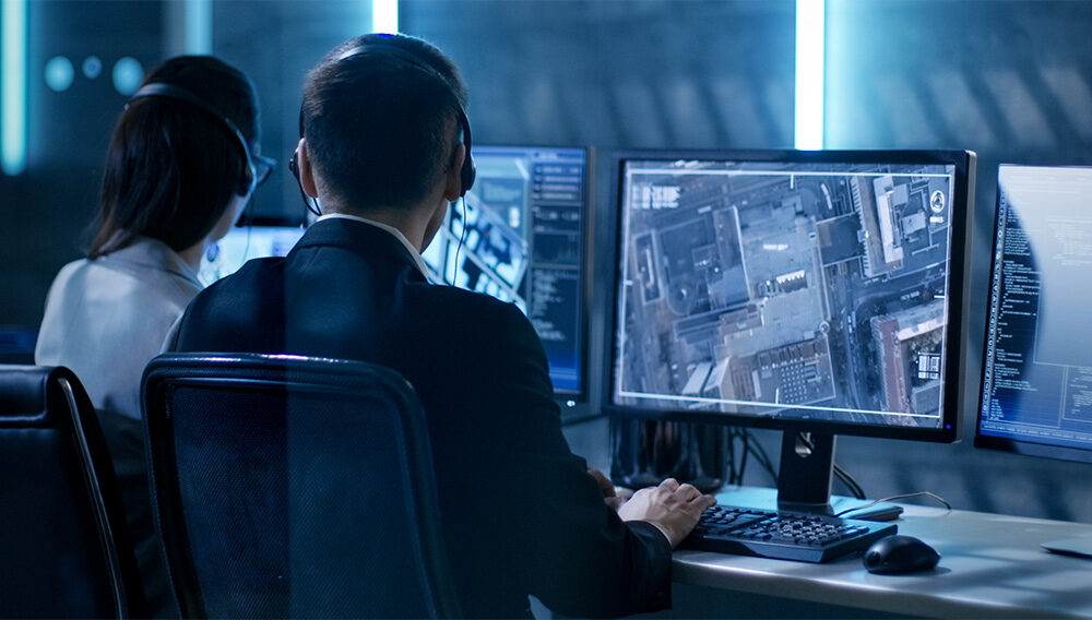 A military dispatcher consults with homeland security officials in the systems control/monitoring room inside a government agency.