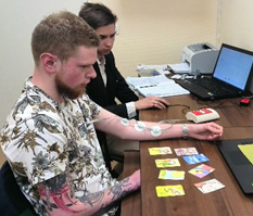 man at desk hooked up to cardiogram while looking at cards