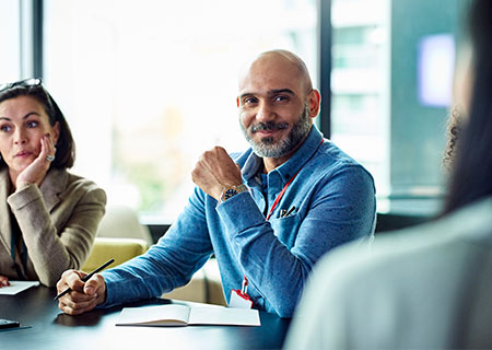 male veteran sitting at board room table politely listening to someone speak