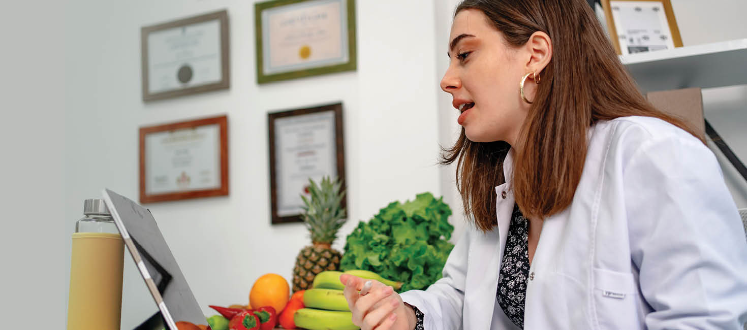 Un nutricionista habla con un paciente junto a un montón de fruta