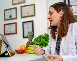 Un nutricionista habla con un paciente junto a un montón de fruta