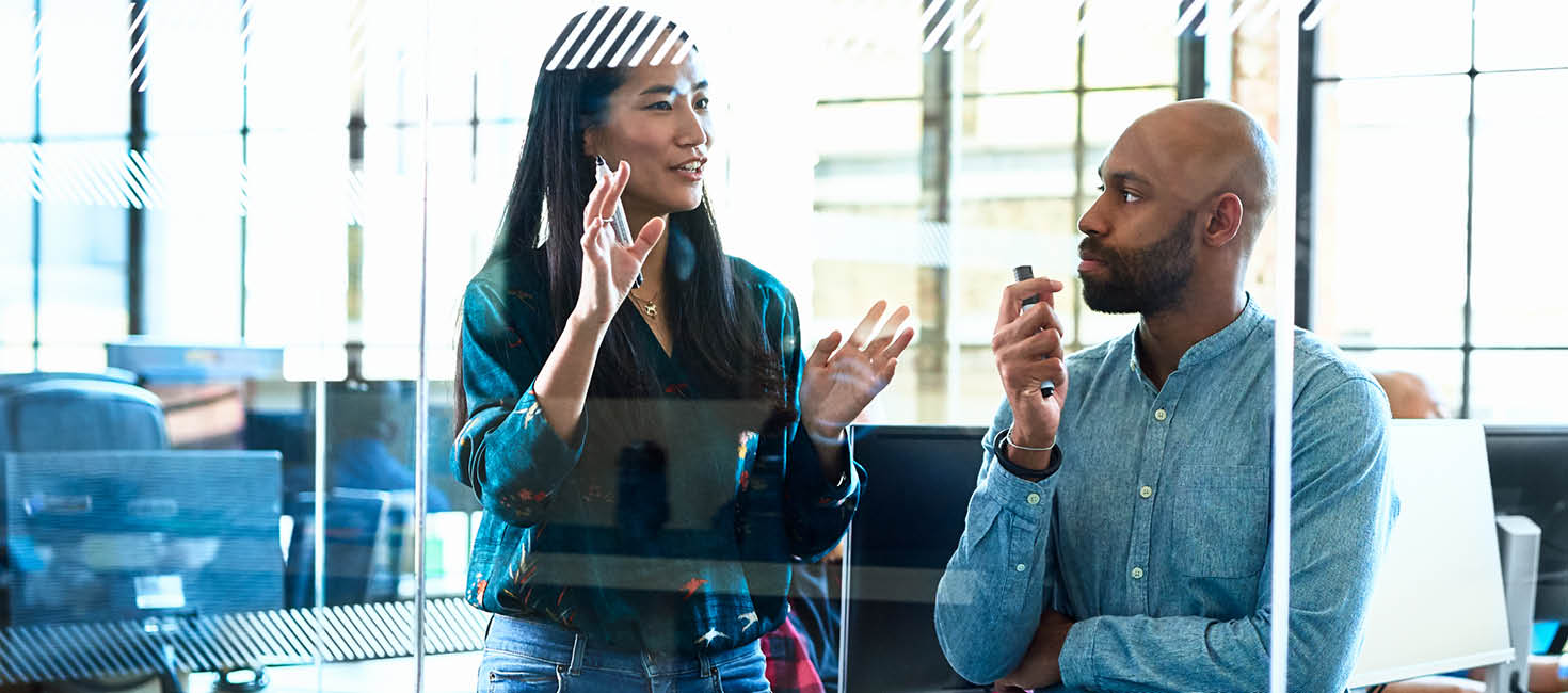 two coworkers discussing a project in an office