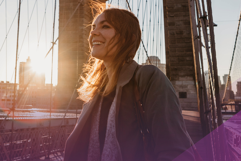 Happy woman looks out over the city at sunrise