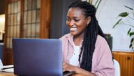 happy woman in her home typing on laptop