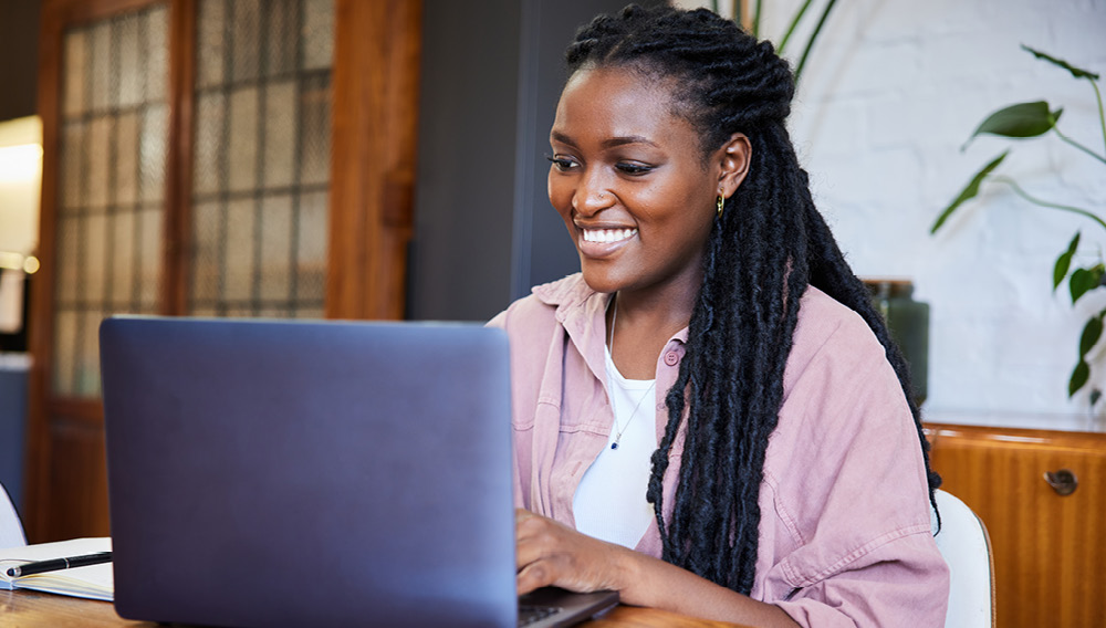 happy woman in her home typing on laptop