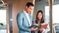 man and woman business professionals looking at tablet