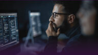 Data specialist, hand on chin, concentrating on a computer screen