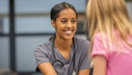 School nurse with stethoscope around her neck, smiling at child