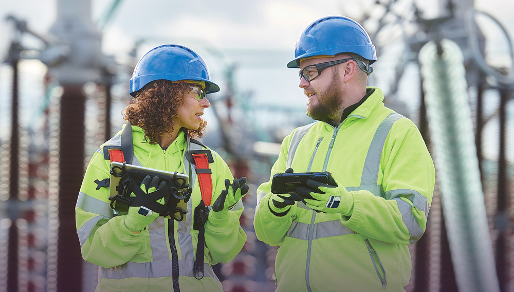 Two electrical engineering technologists discuss readings at an electricity substation.