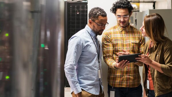 Three IT professionals reviewing data in a server room