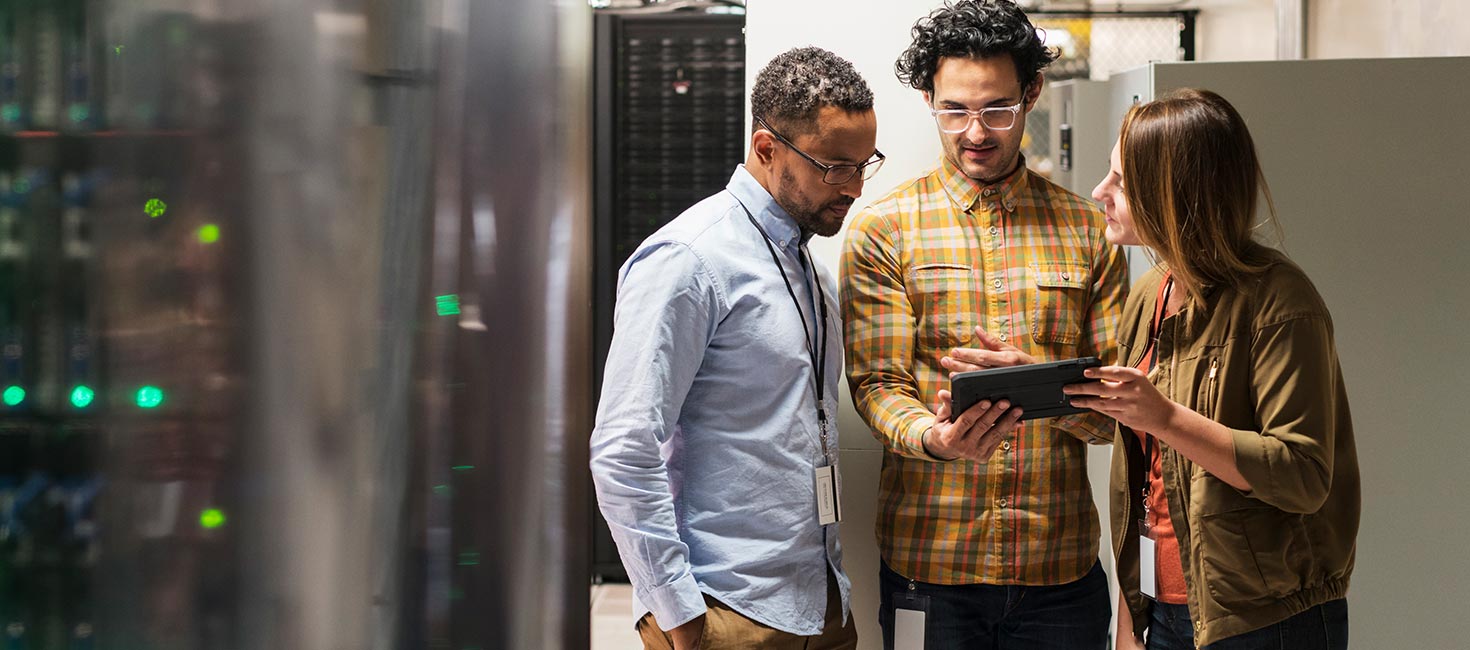 Three IT professionals reviewing data in a server room