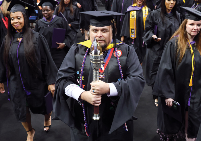 Jason DeLonais carrying the Alumni Torch