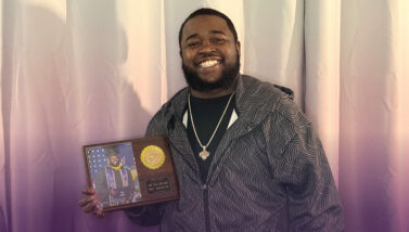 Jatik Gibbs-Judd, nuclear technician, poet, and graduate of Excelsior University’s BS in Nuclear Engineering Technology program in 2025, poses with his Commencement plaque.