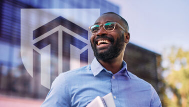 A smiling student stands in front of the Excelsior University logo.