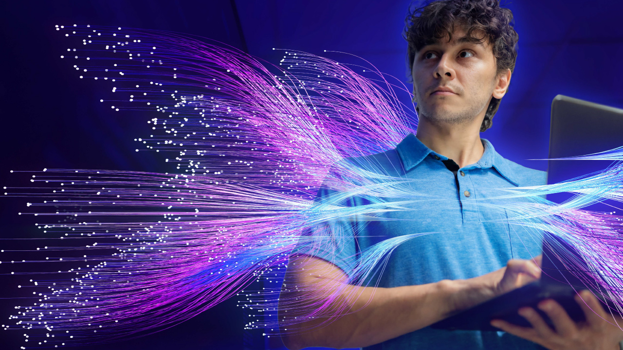 Graphic representation of an IT professional on a laptop, surrounded by purple and blue luminescent fibers representing artificial intelligence