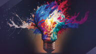 Many colors of paint swirl around a lit incandescent light bulb.