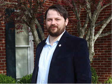 Nathaniel Cox standing in front of a brick building.