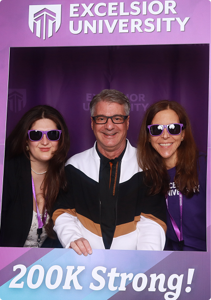 Three people pose together at an Excelsior University photo booth, framed by university branding and a “200K Strong!” banner.