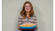 A girl holds a plate of cookies